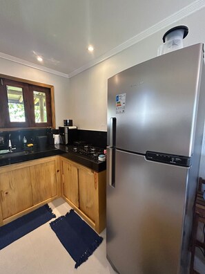 A modern kitchen with wooden cabinets, a stainless steel refrigerator, and a black countertop.