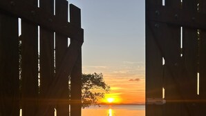A wooden gate leading to a beach with a boat and the sun setting in the background. - Casa Amare Taipu de Dentro - Beachfront property on the Maraú Peninsula (Maraú)