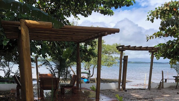 Eine Holzterrasse mit Bänken und einer Pergola mit Blick auf einen Strand.