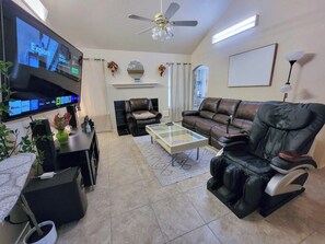 A living room with a flat-screen TV, leather sofas, a massage chair, and a coffee table. - Entire house/Large TVs in all rooms/ Massage Chair/Gym/Grill (Houston)
