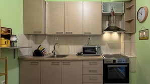 A compact kitchen with light-colored cabinets, a microwave, an oven, and a sink. - Miró by halu! - Cozy apartment on Mitropoleos street (Thessaloniki)