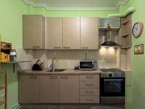 Eine kompakte Küche mit hellen Schränken, einer Mikrowelle, einem Backofen und einem Spülbecken.