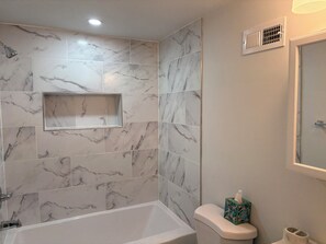 Ein Badezimmer mit einer Badewanne, Toilette und einem Ablagefach mit Taschentuchbox.