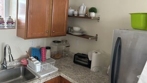 A kitchen with wooden cabinets, a stainless steel refrigerator, a sink, and various kitchen appliances. - 2 bedrooms basement apartment (Washington)