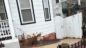 A white house with black window frames, a white picket fence, and a black metal fence. - 2 bedrooms basement apartment (Washington)