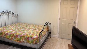 A bedroom with a bed, a door, and a television. - 2 bedrooms basement apartment (Washington)