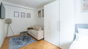 A modern bedroom with a bed, a sofa, a wardrobe, and a floor lamp. - Large, Quiet Maisonette for 10 | 24/7 Check-in (Kapfenberg)