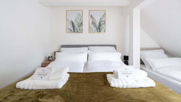 A hotel room with a large bed, two bedside tables, and two framed botanical prints on the wall. - Large, Quiet Maisonette for 10 | 24/7 Check-in (Kapfenberg)