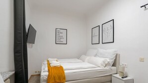 Ein Schlafzimmer mit einem Bett, einem Nachttisch, einer Lampe und zwei gerahmten Motivationssprüchen an der Wand.
