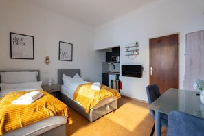 Une chambre d’hôtel avec deux lits, une petite kitchenette, une télévision et un bureau avec une chaise.