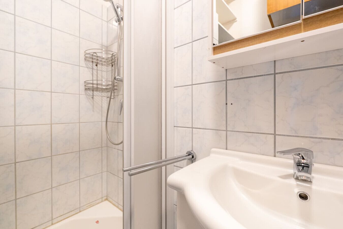 Une salle de bain avec une douche, un lavabo et un miroir.