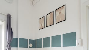 Ett modernt vardagsrum med en beige soffa, en blå, mönstrad matta och turkosfärgade accentpaneler på väggen.
