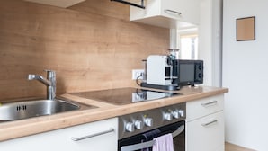 Ett modernt kök med en diskho i rostfritt stål, en inbyggd ugn och en mikrovågsugn placerad på en bänkskiva i trä.