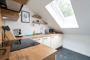 Eine moderne Küche mit Oberlicht, Holzschränken, einer Mikrowelle und einem Spülbecken.