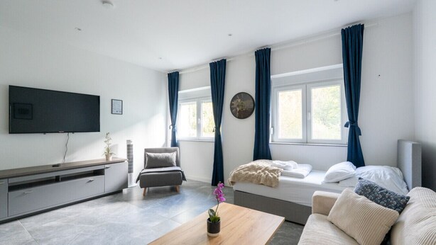 A modern living room with a flat-screen TV, a sofa, a coffee table, and a bed. - 60m² Apt • Business & Family Ready • Near Vienna (Purkersdorf)