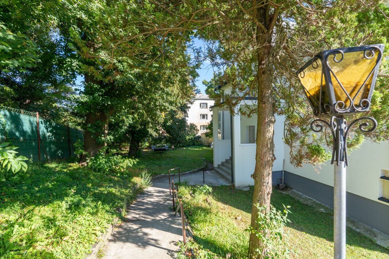 Un camino que lleva a un edificio de fachada blanca y un detalle decorativo amarillo.