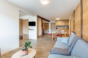 A modern living room with a sofa, a dining table, and a kitchen in the background. - Holiday Apartment '5' with Mountain View and Wi-Fi (Sankt Blasien)