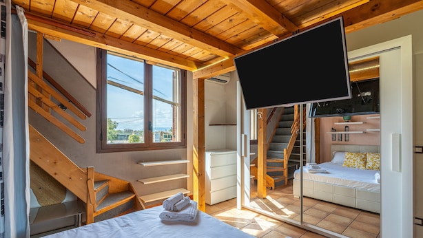 Un dormitorio con cama, televisión, una escalera y una puerta corredera que da a otra habitación.