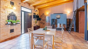 Un comedor con una mesa y sillas de madera, una pared de ladrillo y un reloj en la pared.