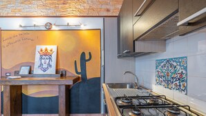 Una cocina con estufa a gas, un lavamanos y un mural en la pared.