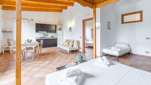 A room with a bed, a dining table with chairs, a kitchen area, and a sofa. - Apartment 'Pathos Retreat Limone' with Shared Pool, Wi-Fi and Air Conditioning (Arenella)