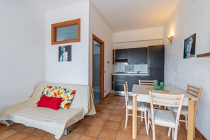 A compact living space with a sofa, a dining table with chairs, a kitchen area, and artwork on the walls. - Apartment 'Pathos Retreat Lavanda' with Shared Pool, Wi-Fi and Air Conditioning (Arenella)