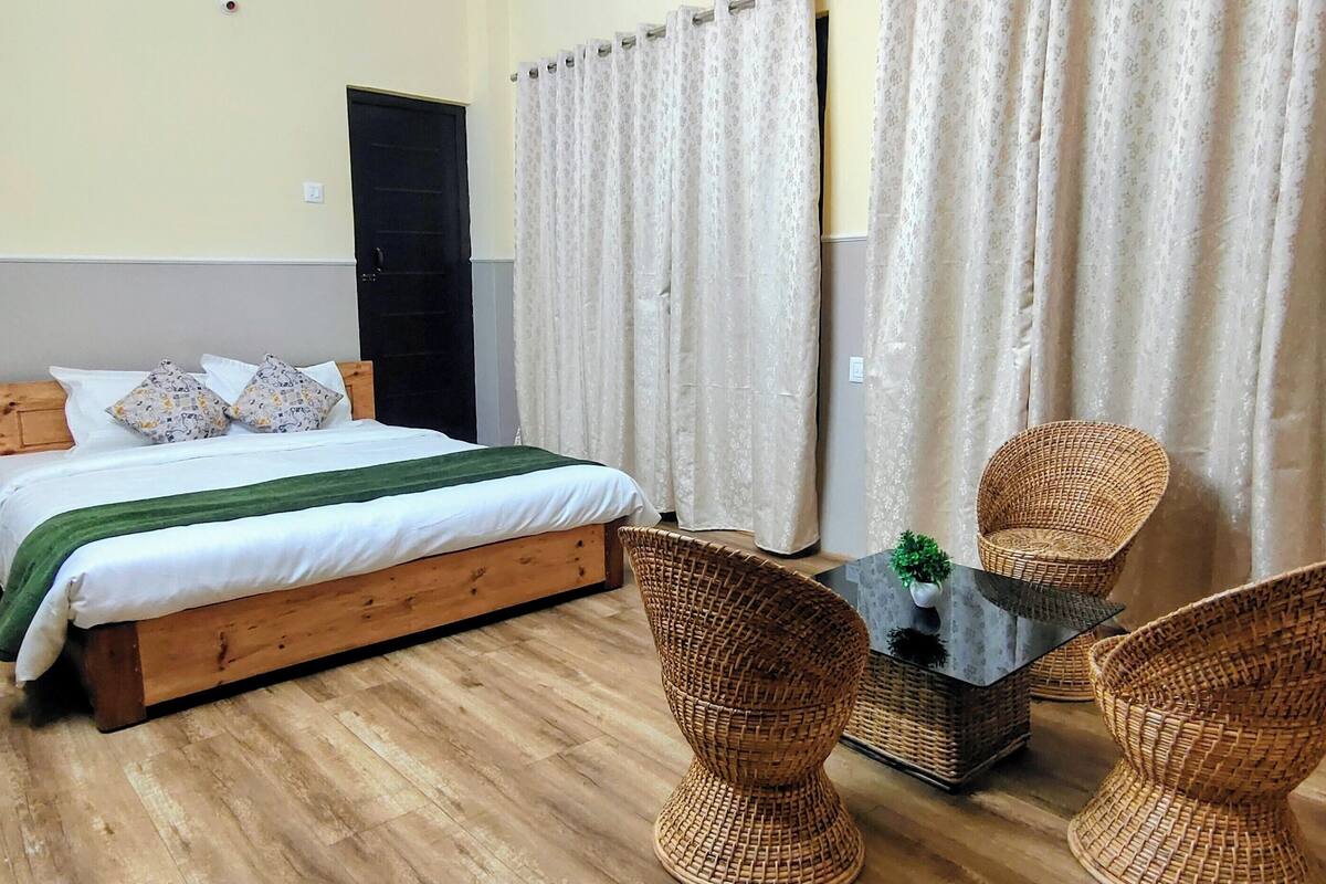 A bedroom with a wooden bed, a small table with a plant, and wicker chairs.