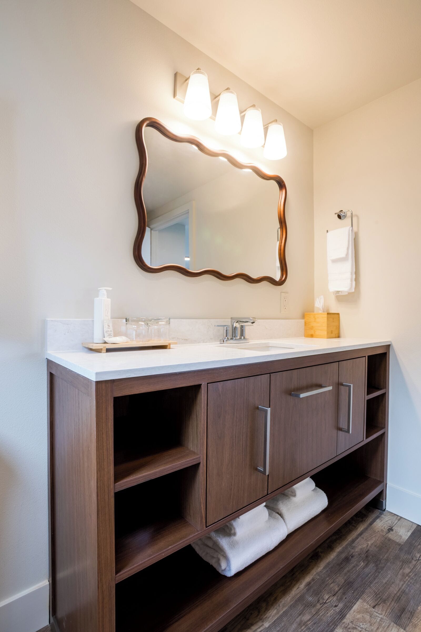 Un baño con tocador de madera, un espejo grande y una lámpara de pared.