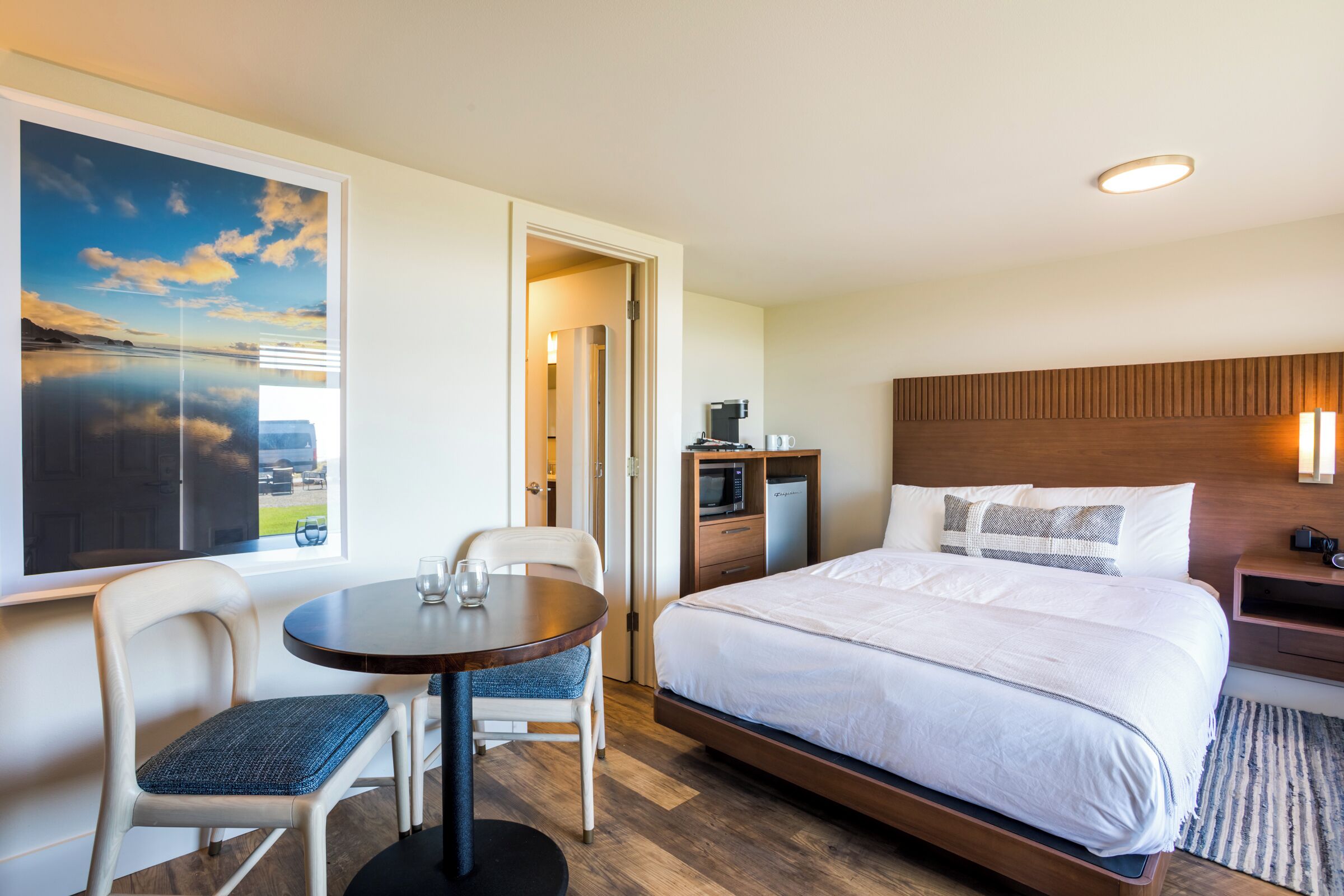 Ein Hotelzimmer mit einem Bett, einem Esstisch mit Stühlen, einer Mikrowelle, einer Kaffeemaschine und einem großen Fenster mit Blick.