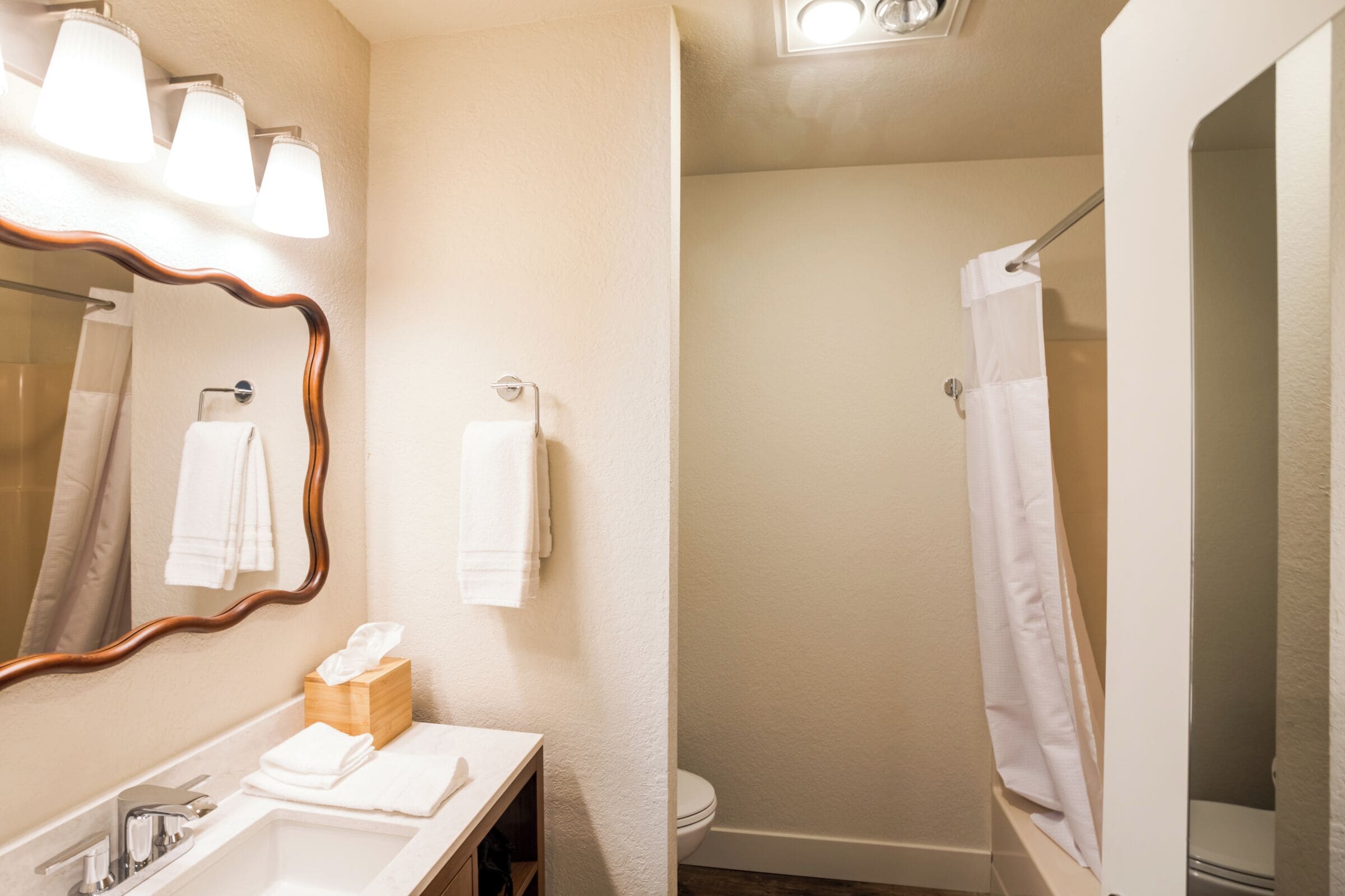 A bathroom with a sink, mirror, towel rack, and a shower curtain.