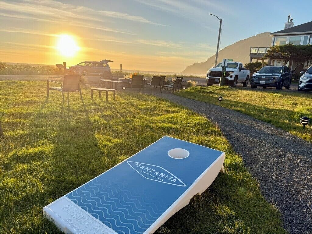 Césped con un juego de mesa azul, un camino y coches estacionados.