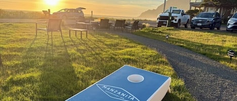 Césped con un juego de mesa azul, un camino y coches estacionados.