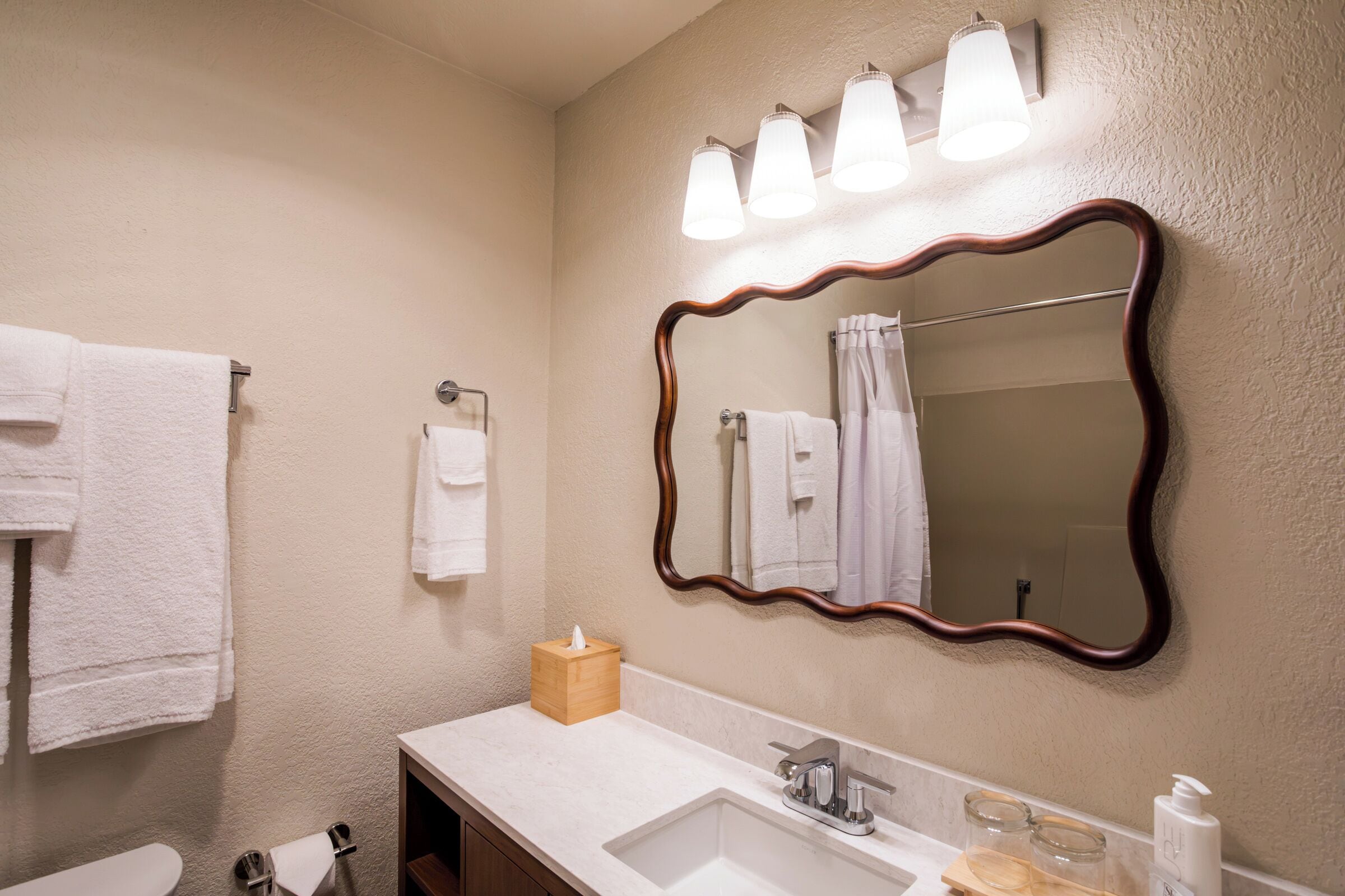 A bathroom with a large mirror, a sink with a faucet, and a towel rack.
