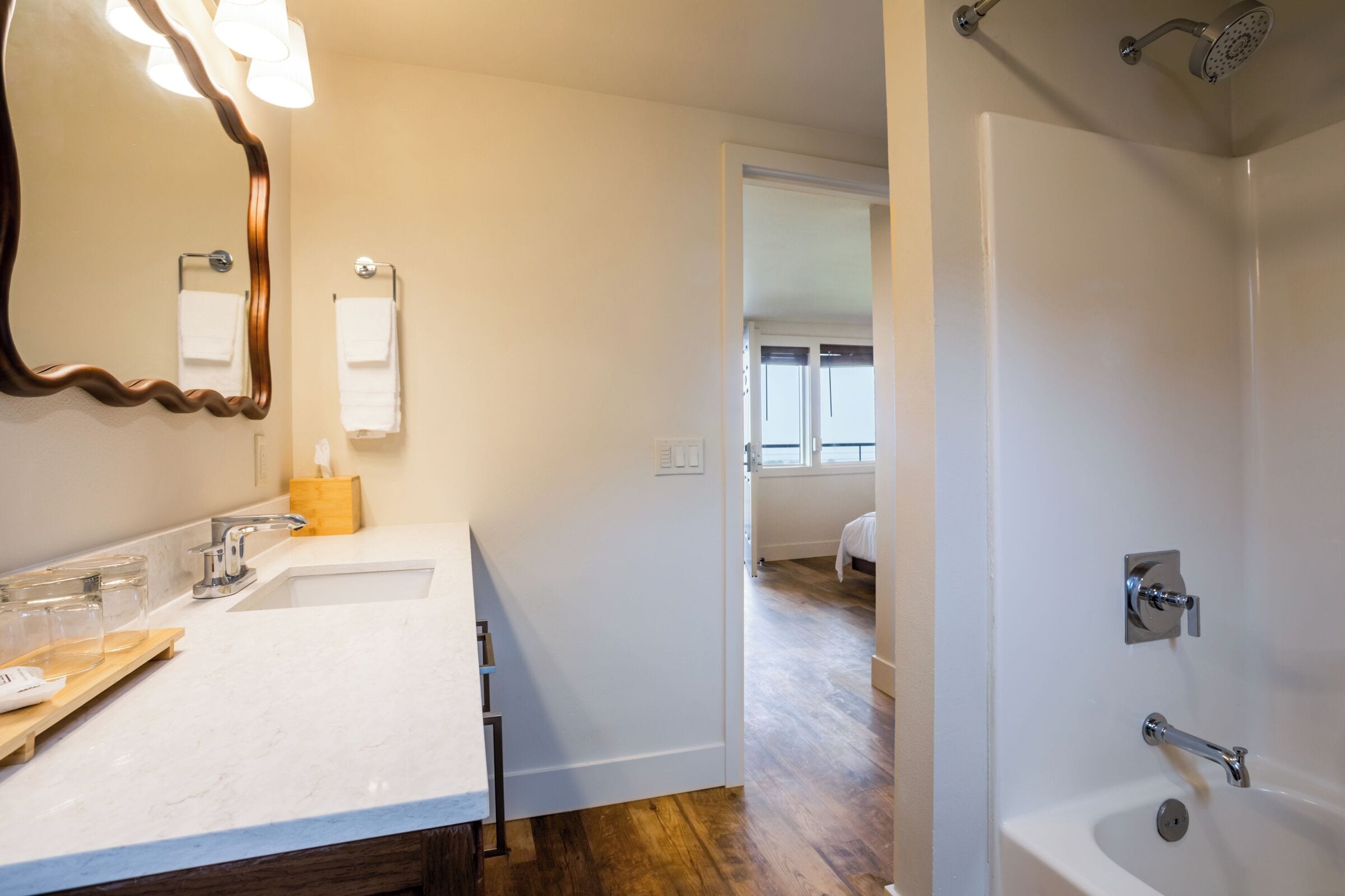 A modern bathroom with a double sink, a mirror, a towel rack, and a shower.