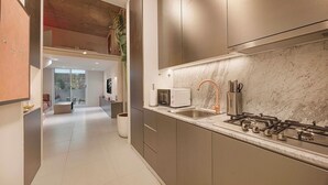 A modern kitchen with a gas stove, a microwave, and a sink. - Private Patio / Gym / Sauna / Loft / Fast Wifi (Dubai)