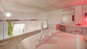 A hotel room with a bed, a bedside table, a mirror, a red light, and a potted plant. - Private Patio / Gym / Sauna / Loft / Fast Wifi (Dubai)