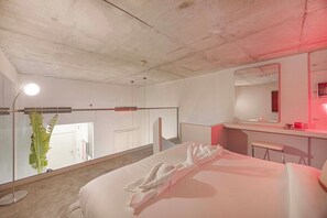 A hotel room with a bed, a bedside table, a mirror, a red light, and a potted plant. - Private Patio / Gym / Sauna / Loft / Fast Wifi (Dubai)