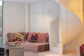 A modern interior with a curved white wall, a sofa with patterned cushions, and a small table. - Private Patio / Gym / Sauna / Loft / Fast Wifi (Dubai)