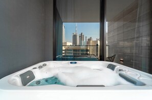 Ein Whirlpool mit Blick auf die Stadt durch eine Glasdoor.