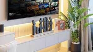 Un soggiorno moderno con una TV a schermo piatto fissata al muro, che mostra diversi poster di film.