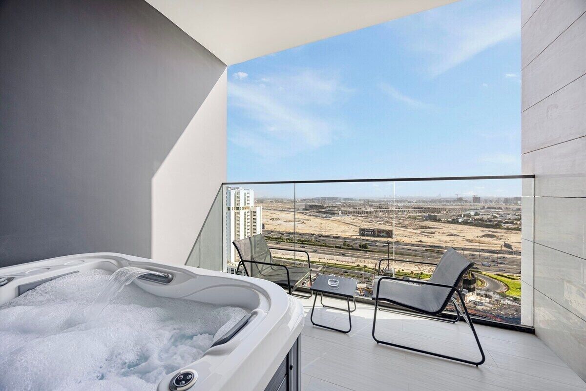 Et moderne badeværelse med jacuzzi og en balkon med glasværn og udsigt over byen.