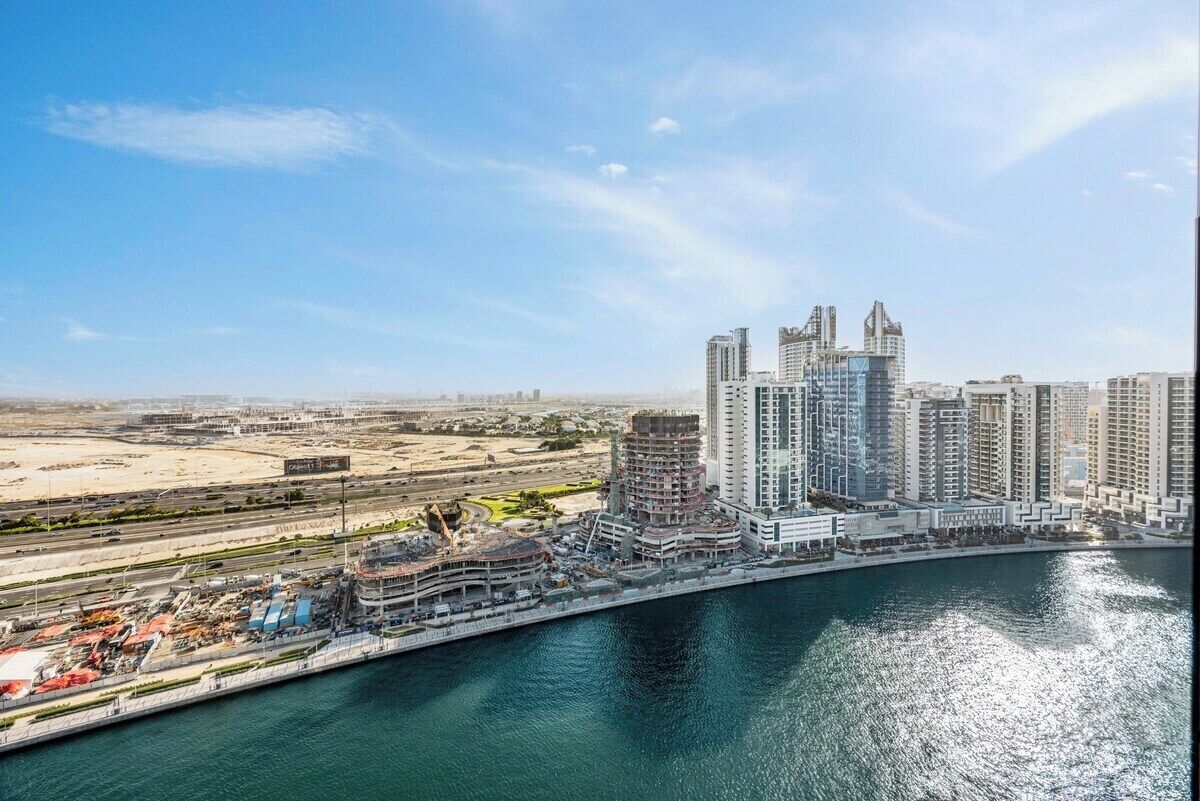 A coastal cityscape with high-rise buildings, a marina, and a desert landscape in the background.