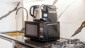 Eine kleine Küche mit Mikrowelle, Kaffeemaschine und Wasserkocher auf einer Arbeitsfläche.