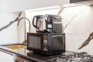 Eine kleine Küche mit Mikrowelle, Kaffeemaschine und Wasserkocher auf einer Arbeitsfläche.