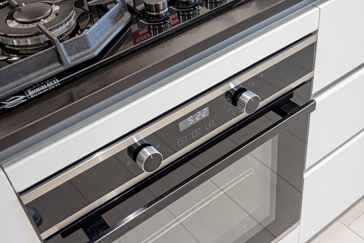 Een moderne keuken met een roestvrijstalen afzuigkap en een digitaal scherm.