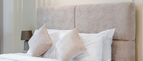 Un lit avec une tête de lit, des oreillers et une table de chevet avec une lampe.
