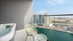 Ein Balkon mit Whirlpool, einem Stuhl und Blick auf eine Stadtlandschaft.