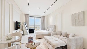Ein modernes Hotelzimmer mit einem großen Bett, einer Couch, einem Esstisch und einem Fernseher.