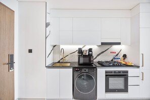 A compact kitchen with a built-in washer, oven, and microwave. - Private Jacuzzi / Canal View / Pool & Cold Plunge (Dubai)
