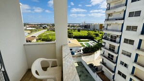 Ein Balkon mit Blick auf ein Wohngebiet, ein weißer Stuhl und ein kleines Schwimmbecken.